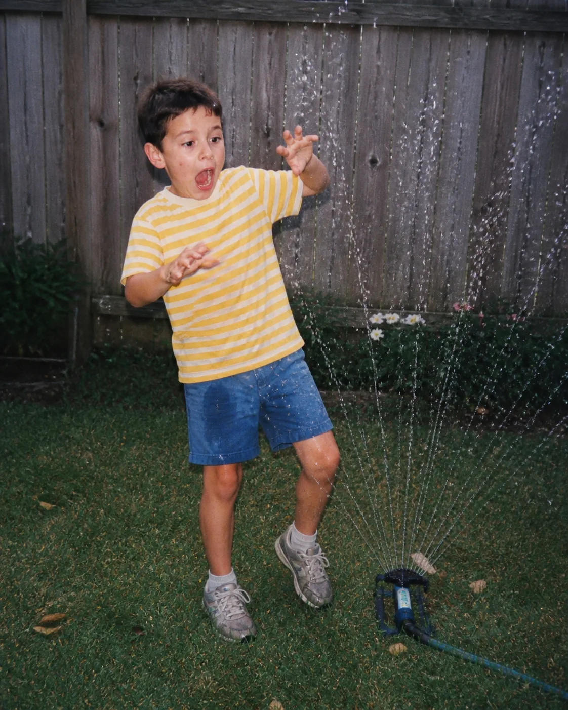 Alex as a child surprised by a garden sprinkler