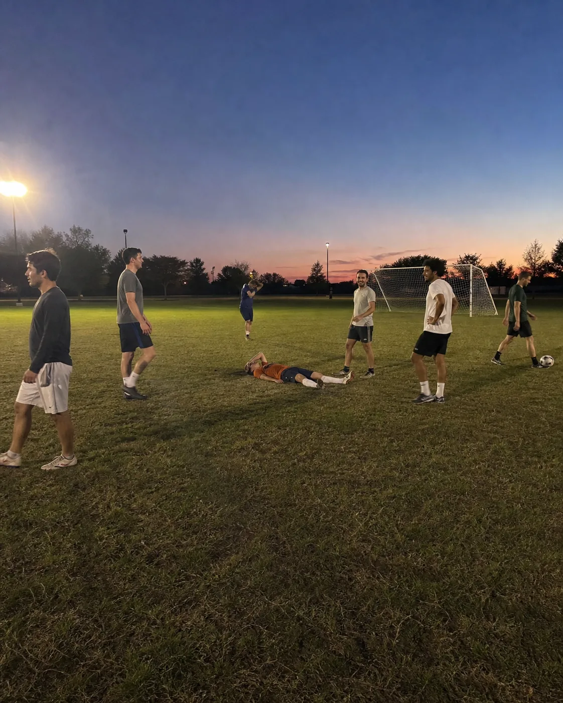 Alex lying exhausted on a football field among friends